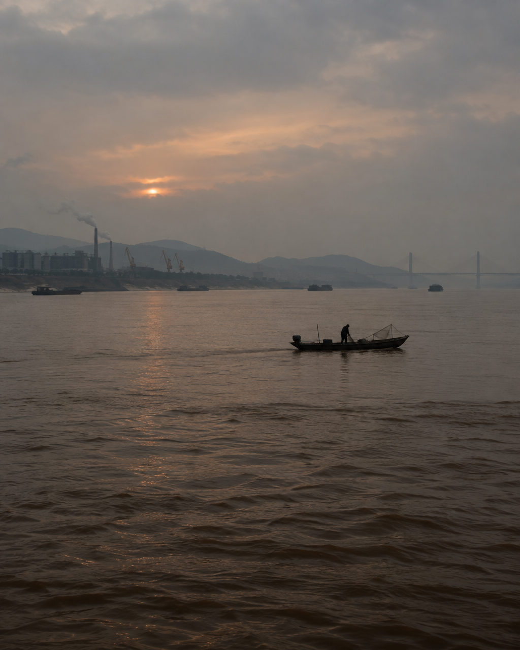 El río Yangtsé, ancho y de aguas marrones, al atardecer, con un bote pesquero pequeño en la distancia y orillas industriales