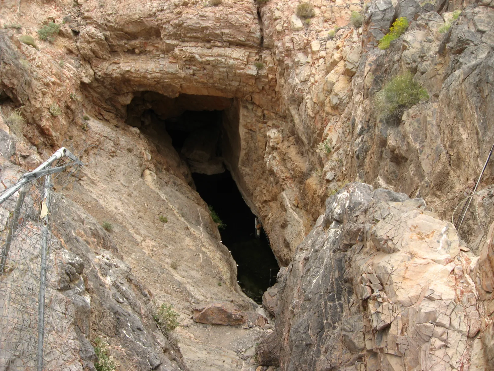 La entrada de la grieta de Devils Hole entre rocas del desierto de Nevada, rodeada por una cerca de protección